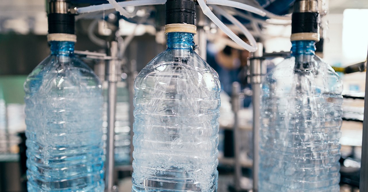 Robotic factory line for processing and bottling of pure spring water into canisters and bottles. Selective focus. Short depth of field.