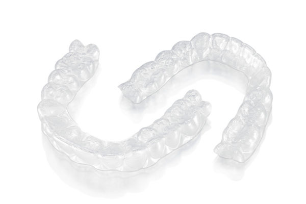Photo of 3M™ Clarity™ Aligners on a white background and laying down outside of the case.