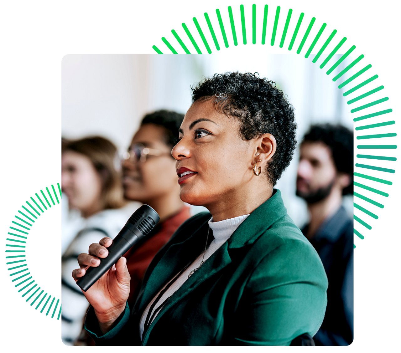 Woman speaking into microphone in front of crown wearing a green jacket