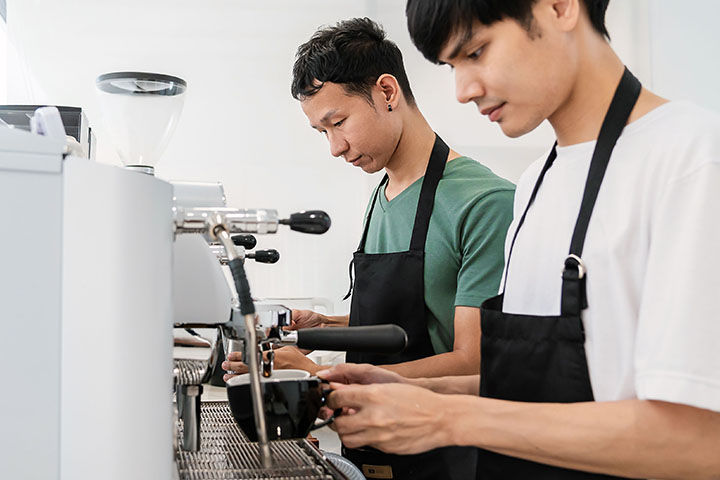 Two male baristas making espresso in a coffee shop