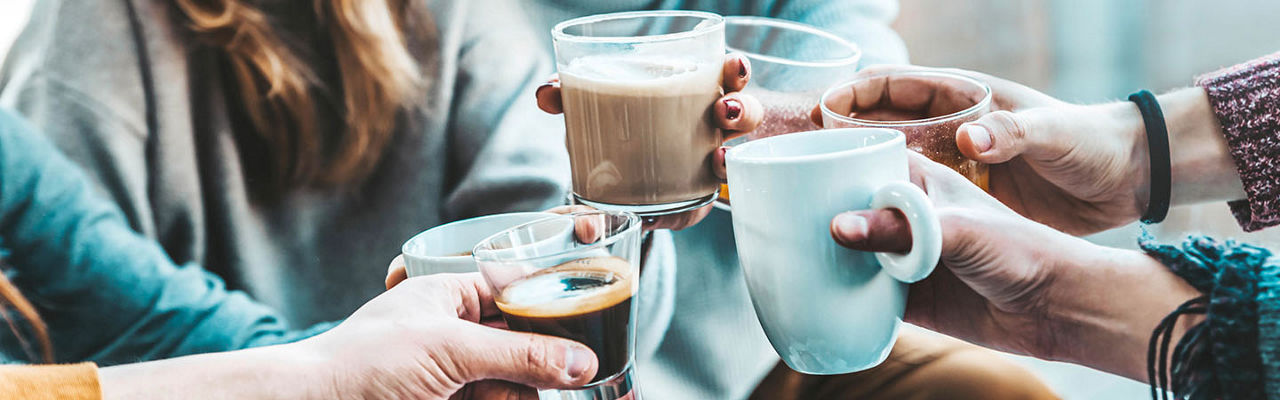 A group of hands holding various coffee beverage cheering together