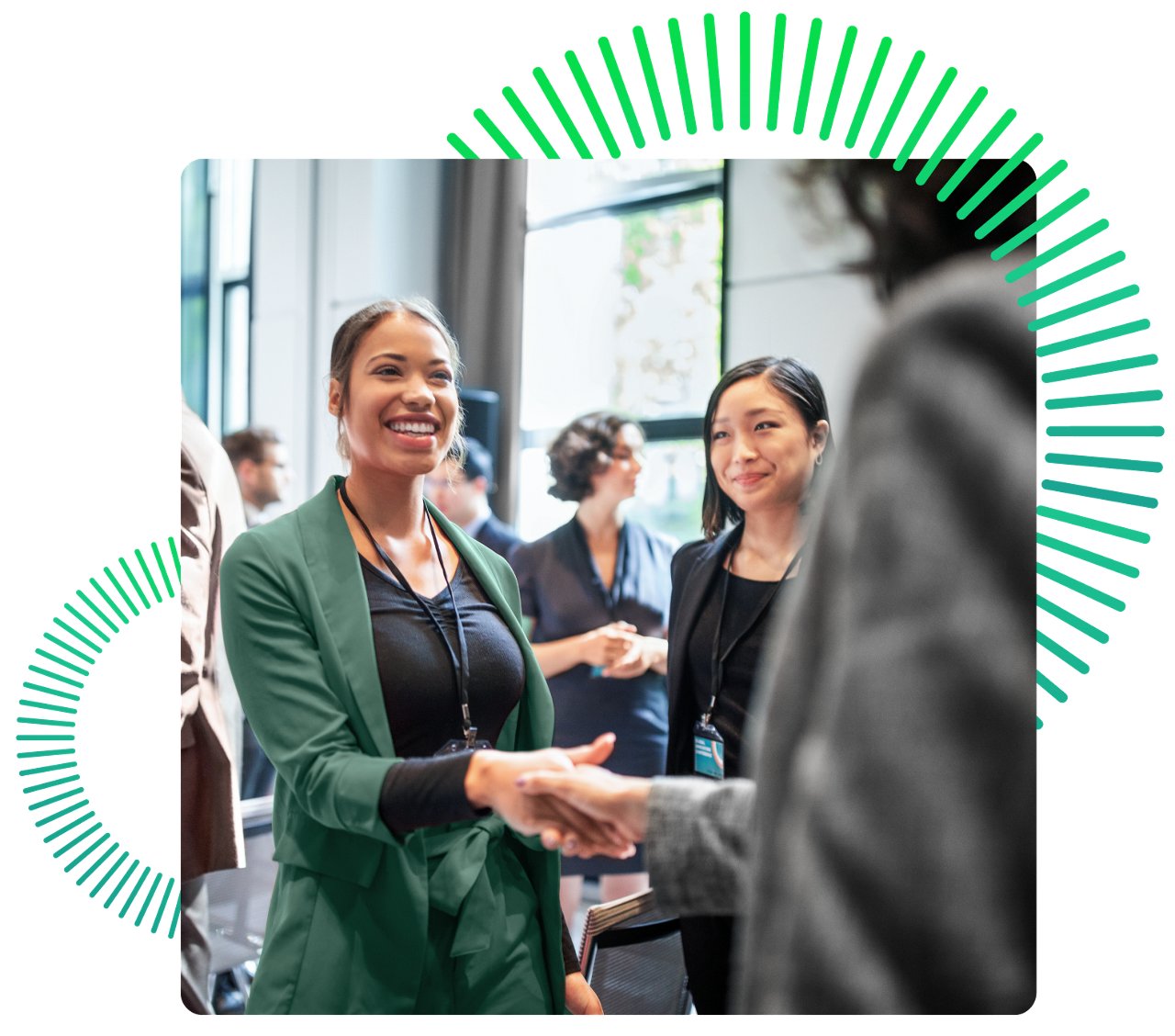 Woman shaking hands with attendee while another woman smiles in the background