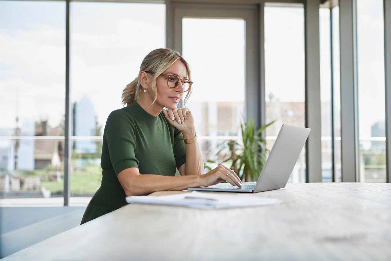 Confident mature woman using laptop on table at home.