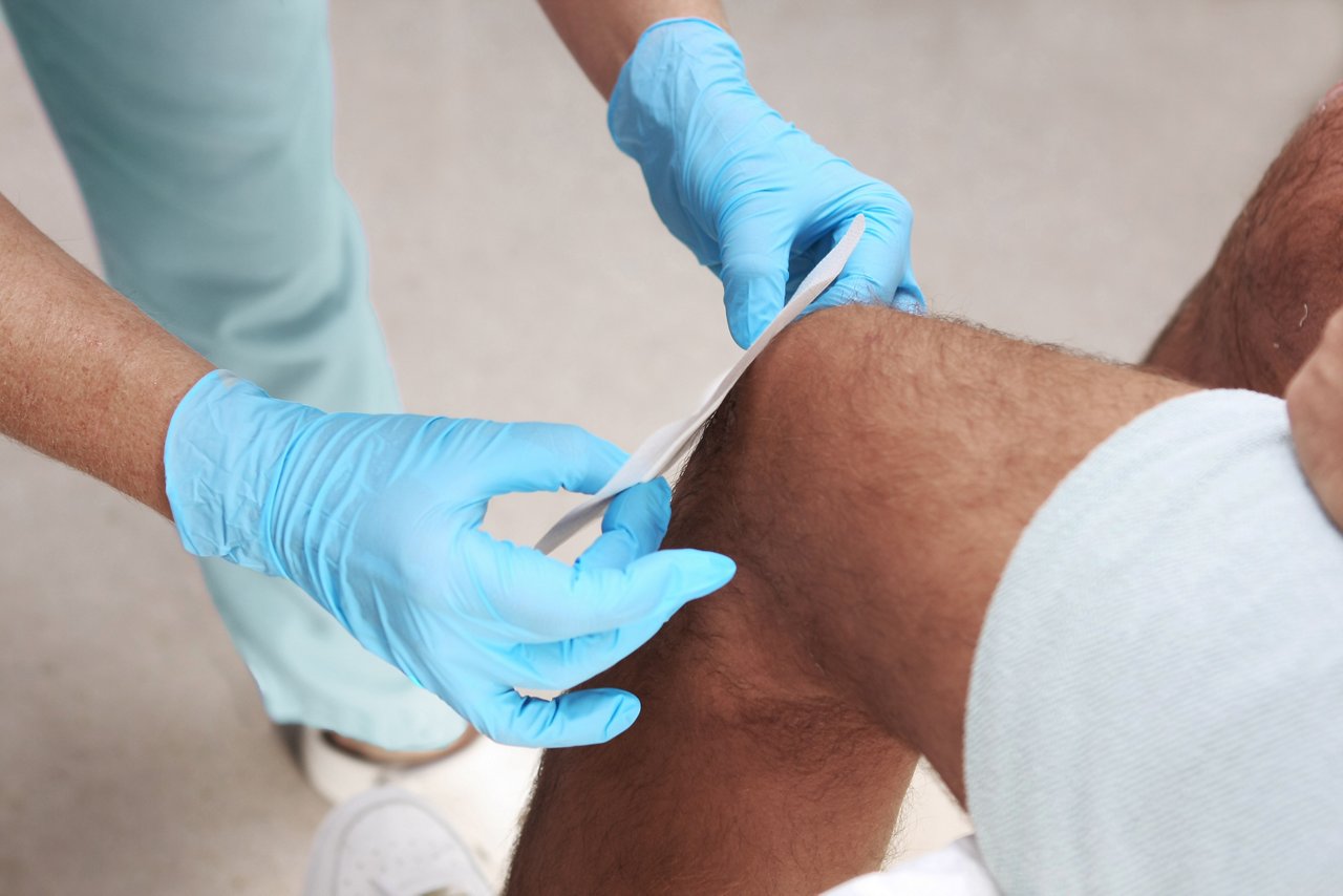 Nurse applying a bandage on a wounded knee.