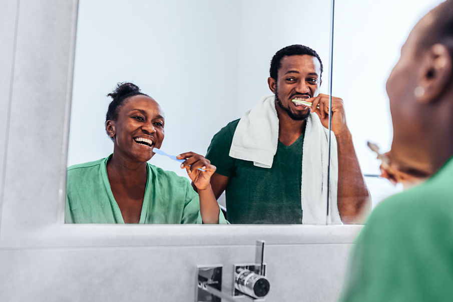 Reflection of couple brushing teeth in bathroom