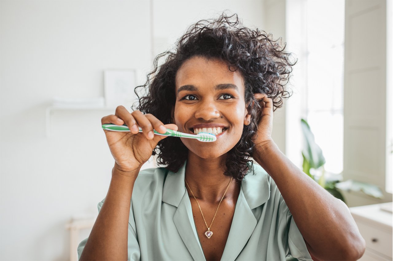 Smiling woman brushing healthy teeth in bathroom, Serbia and Montenegro