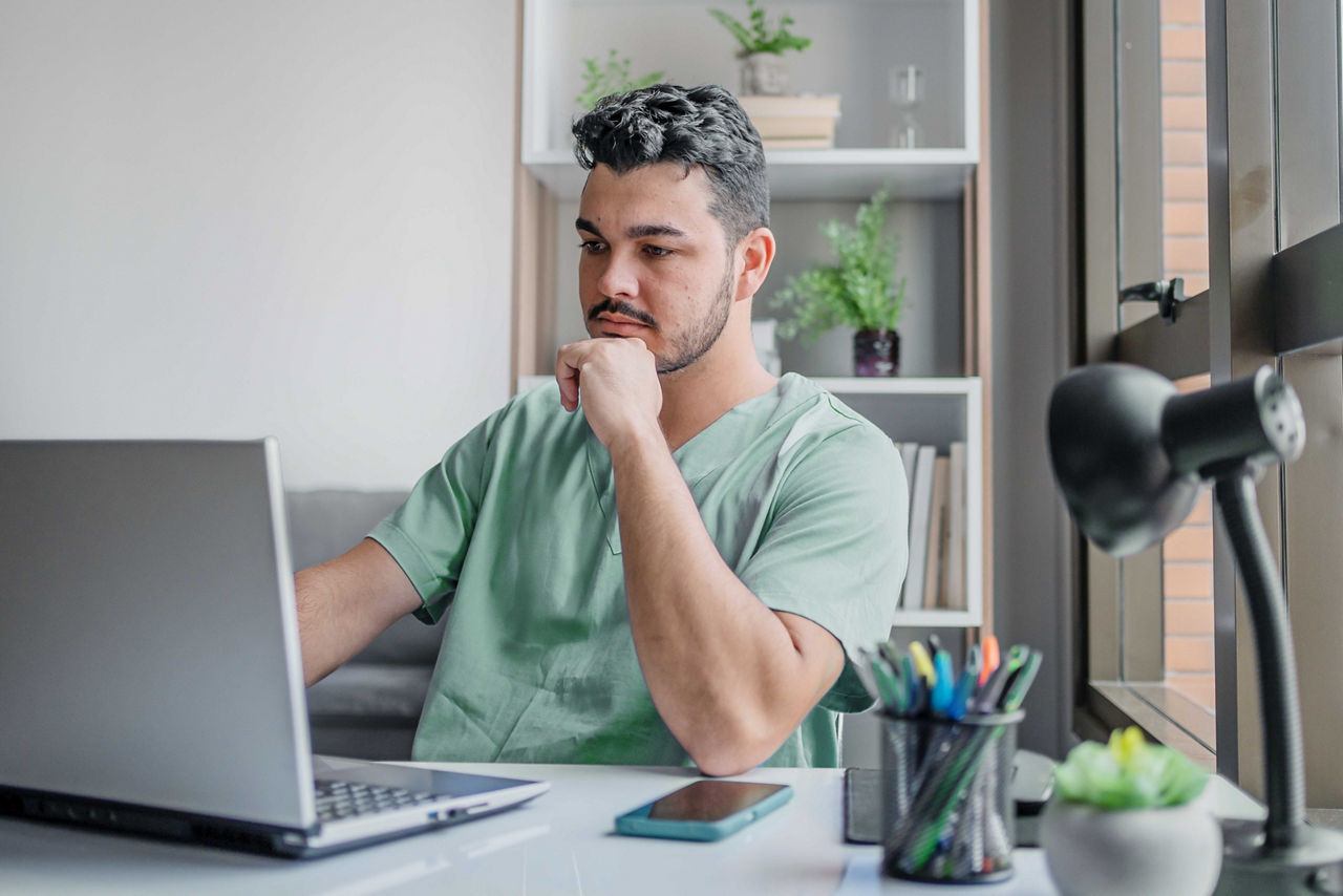 Uomo riflessivo che utilizza un laptop alla sua scrivania in ufficio.