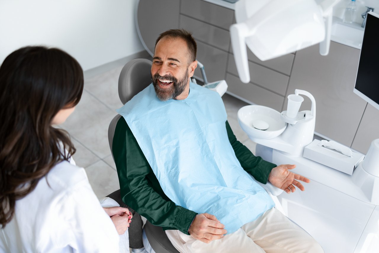 Happy mid adult man communicating with his dentist during an exam in dentist's office.
