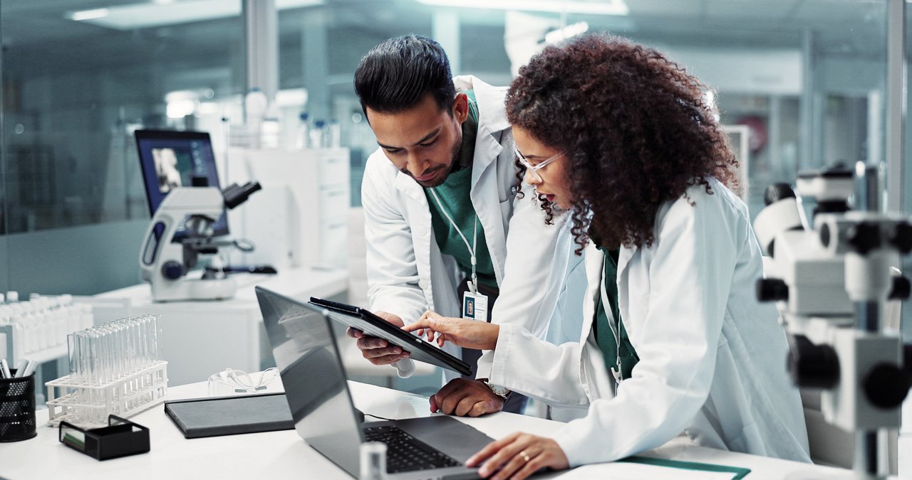 two lab workers examining a tablet.