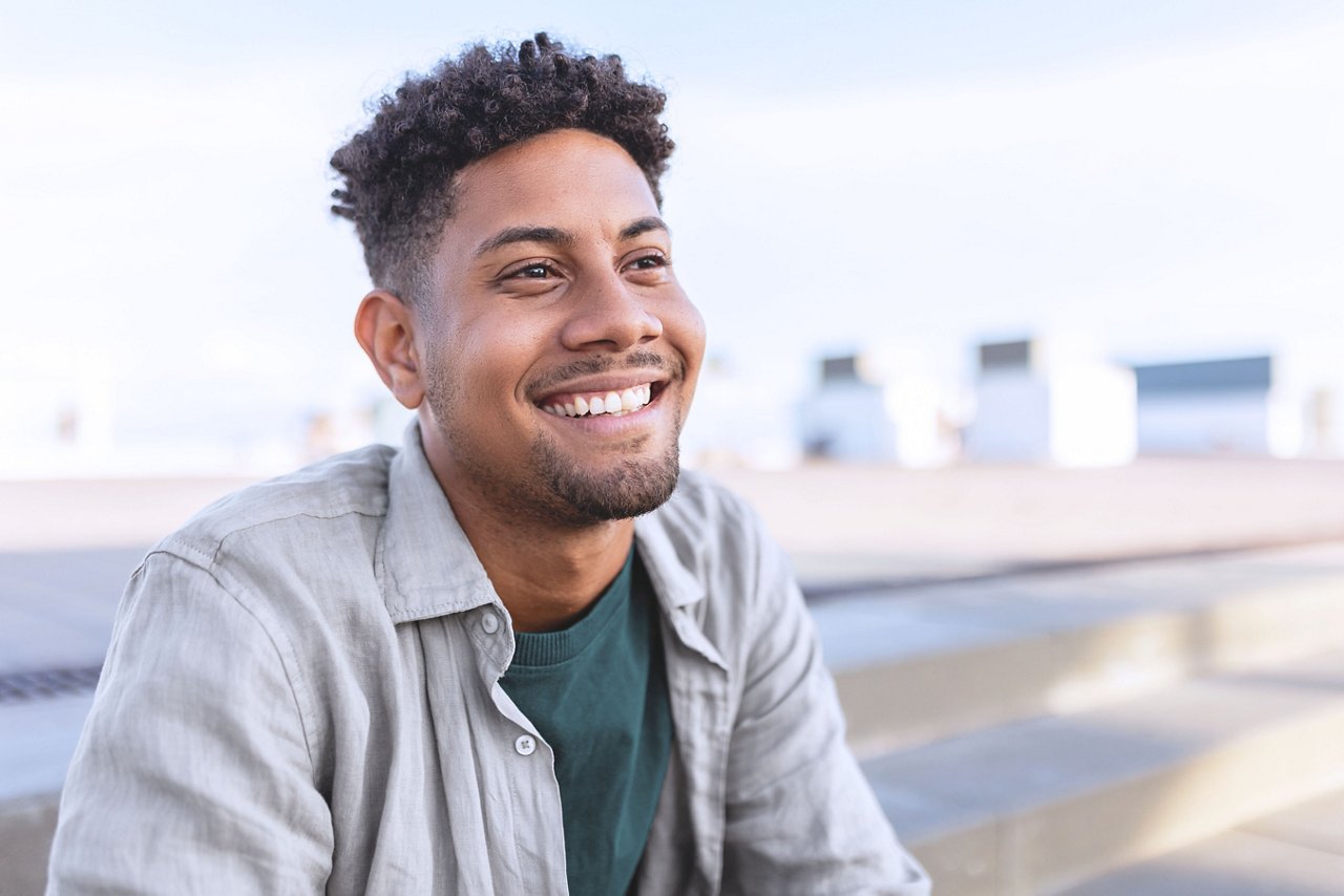 Portrait of young smiling African American man sitting outdoors.