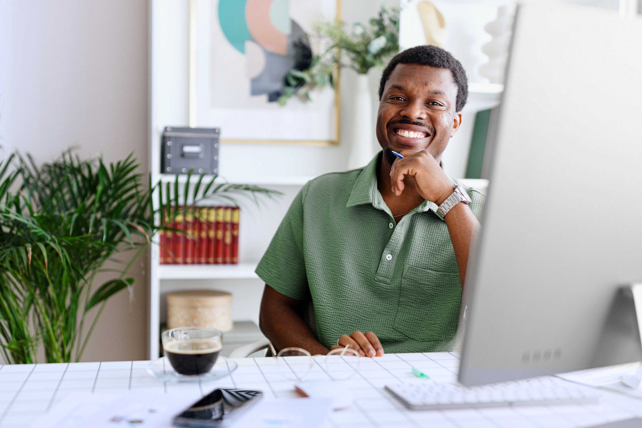 Portrait of a smiling african-american man working from his desk at home.