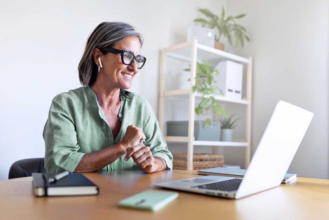 Smiling mature businesswoman having a video call on her laptop in her home office.