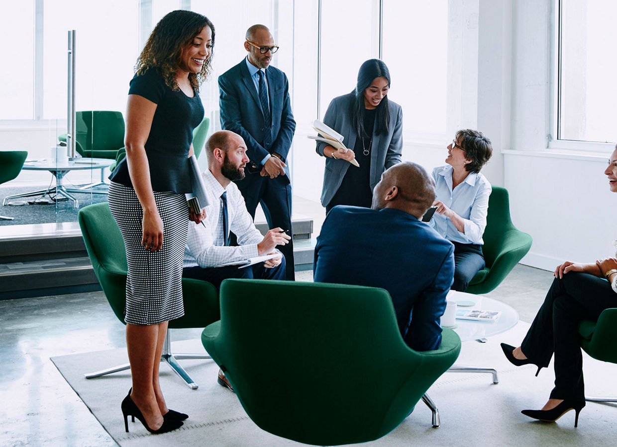 Image of several business professionals interacting in an open-plan office environment.