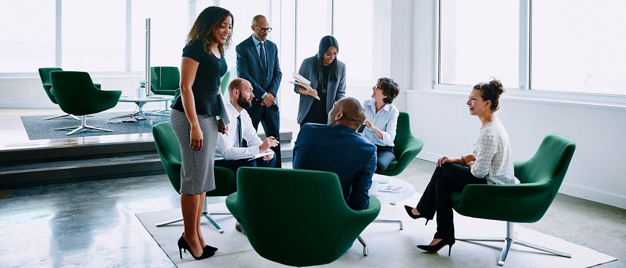 Several business professionals interacting in an open office setting.