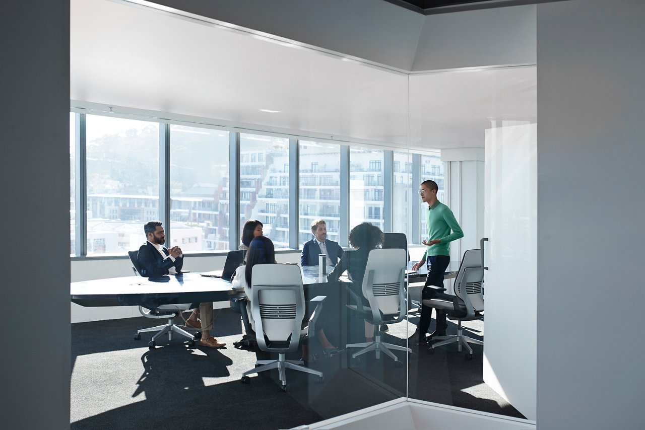 Young male entrepreneur presenting to a small group of business people in an office boardroom.