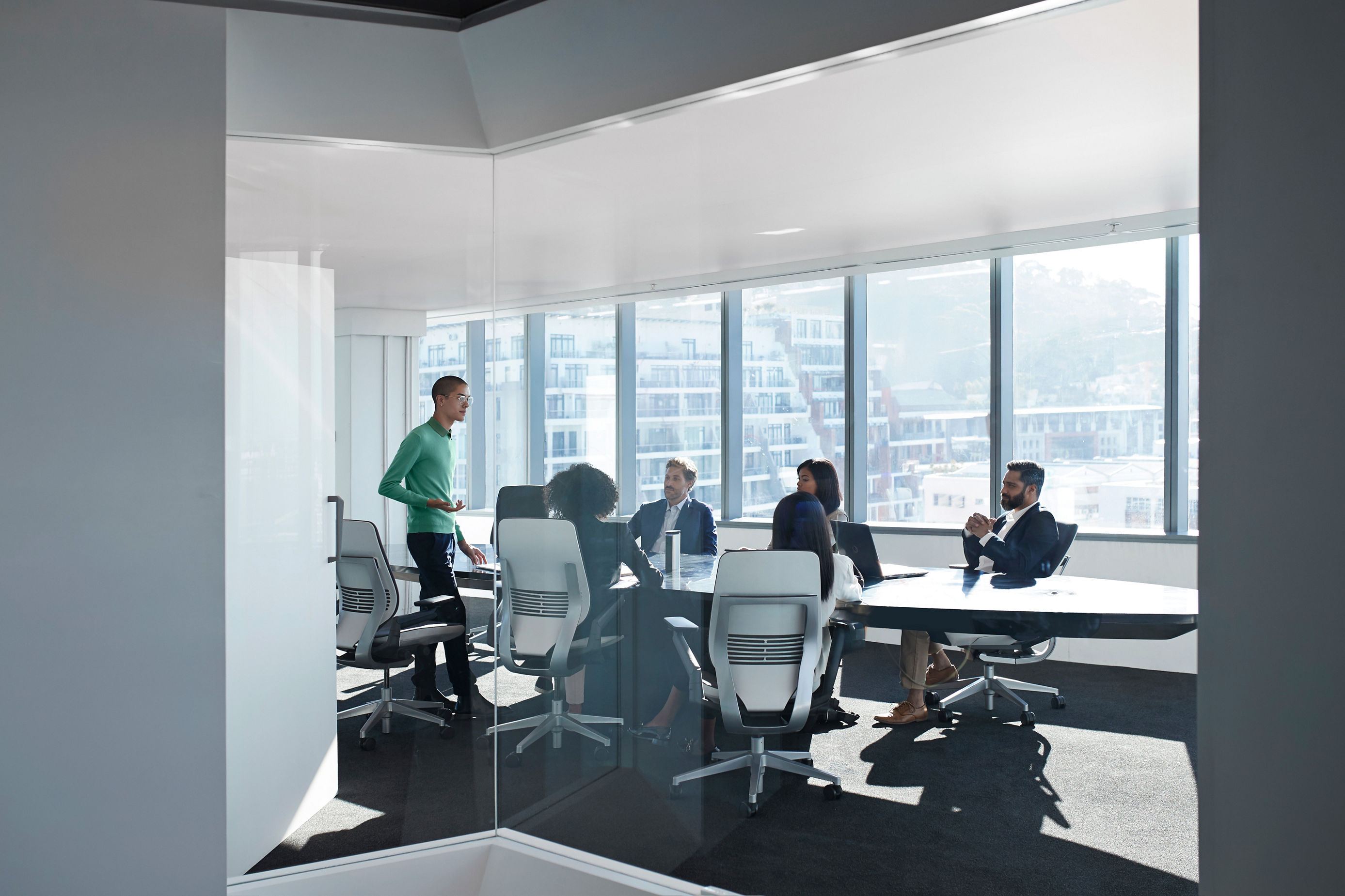 Young male entrepreneur presenting to a small group of business people in an office boardroom.