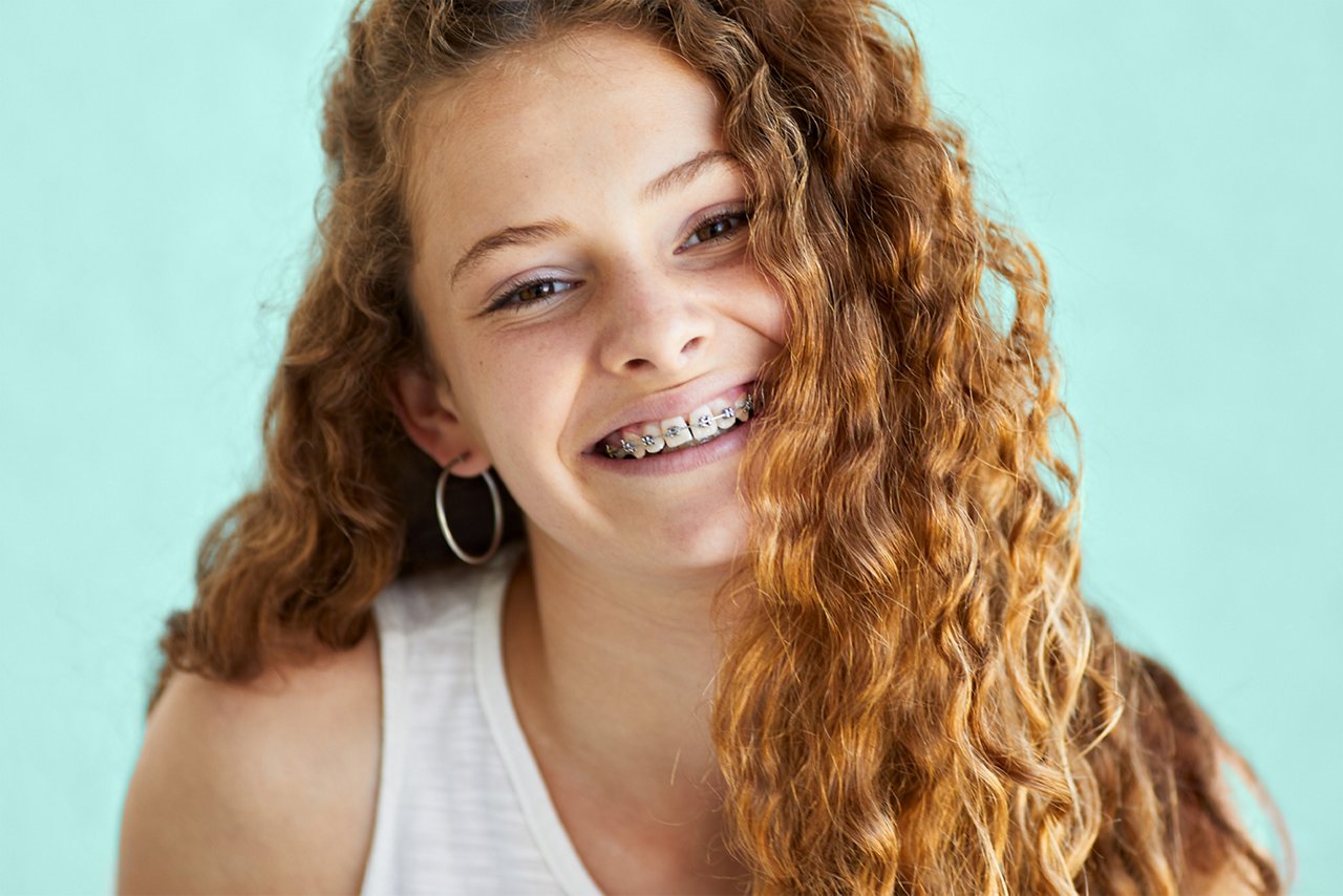 Una imagen de una niña con brackets sonriendo a la cámara