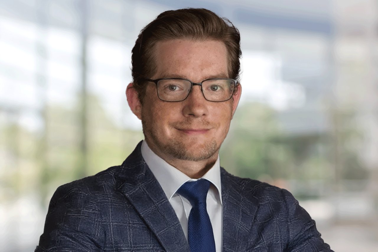 Headshot of a smiling man with glasses wearing a suit