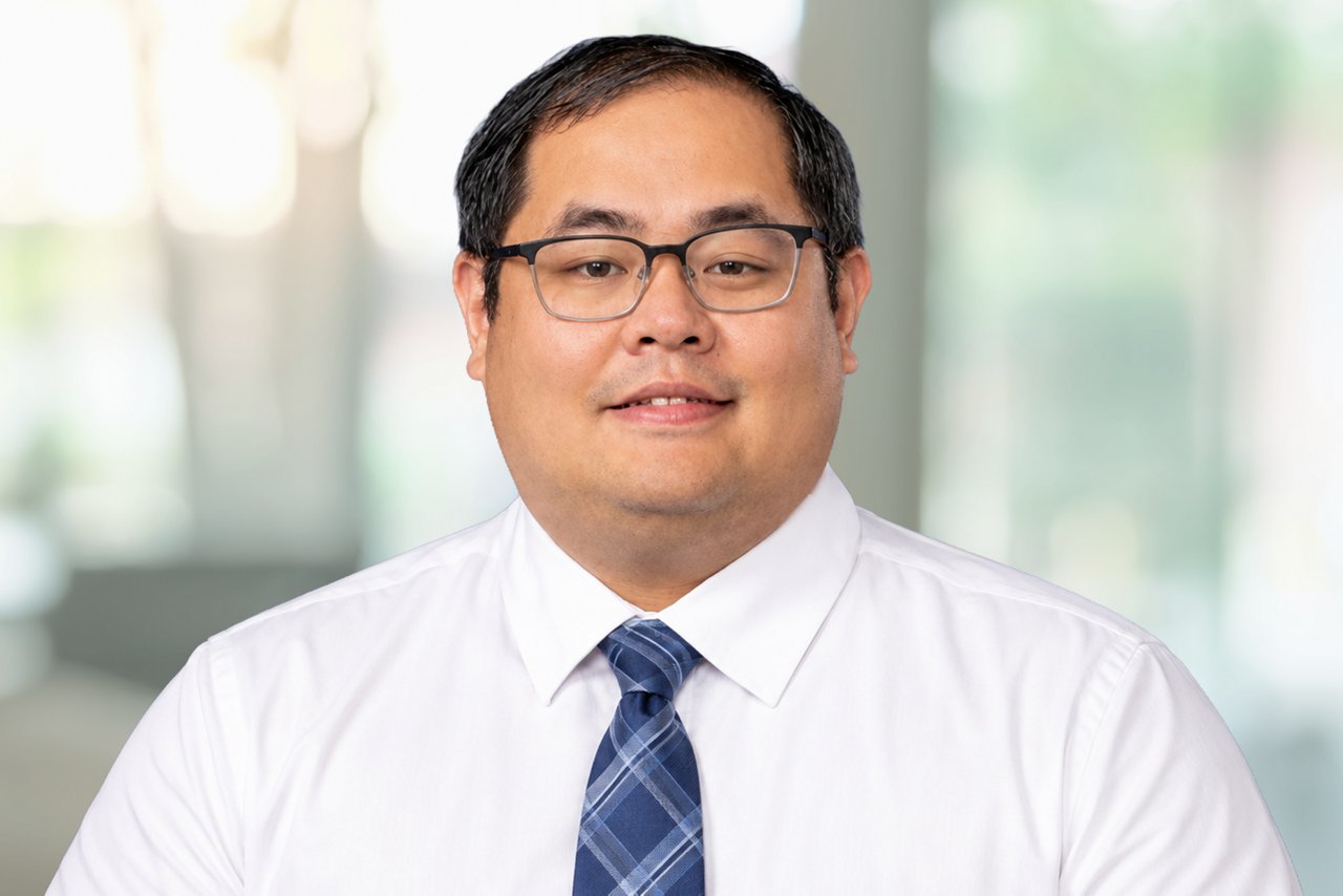 A smiling man in glasses and a tie.