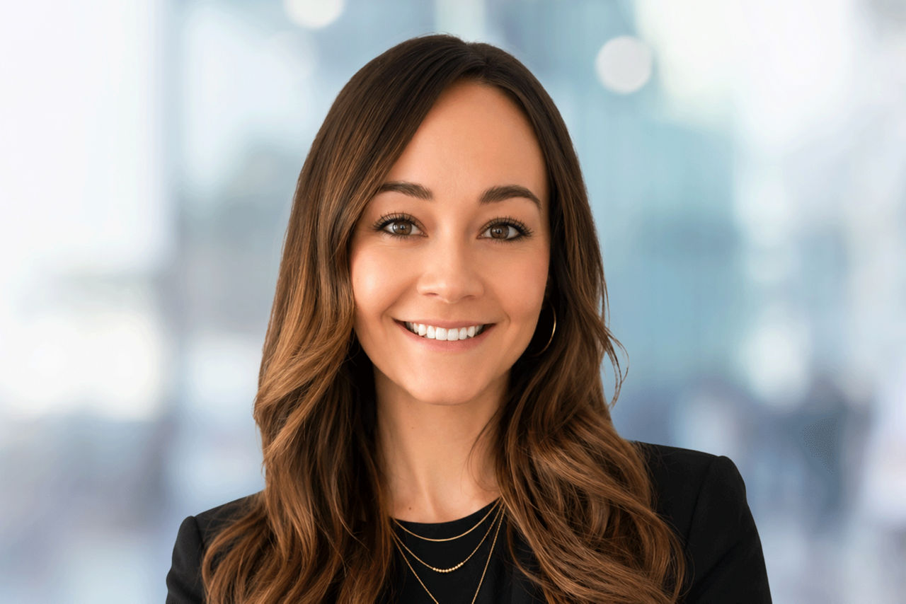 Head shot of a woman wearing glasses and black shirt in an office setting.