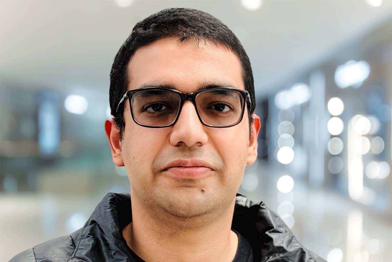 Utkarsh Tripathi head shot, a man wearing glasses, smiling in a jacket against an office background.