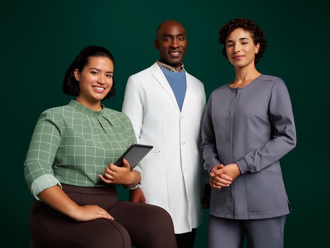 Groepsportret van een team van drie orthodontische professionals tegen een donkergroene achtergrond.