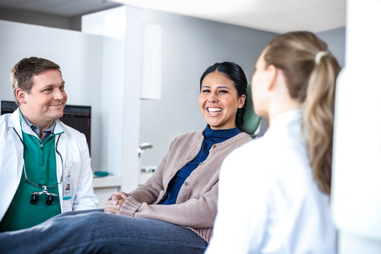 A patient and two dental professionals have a conversation in a modern dental office.