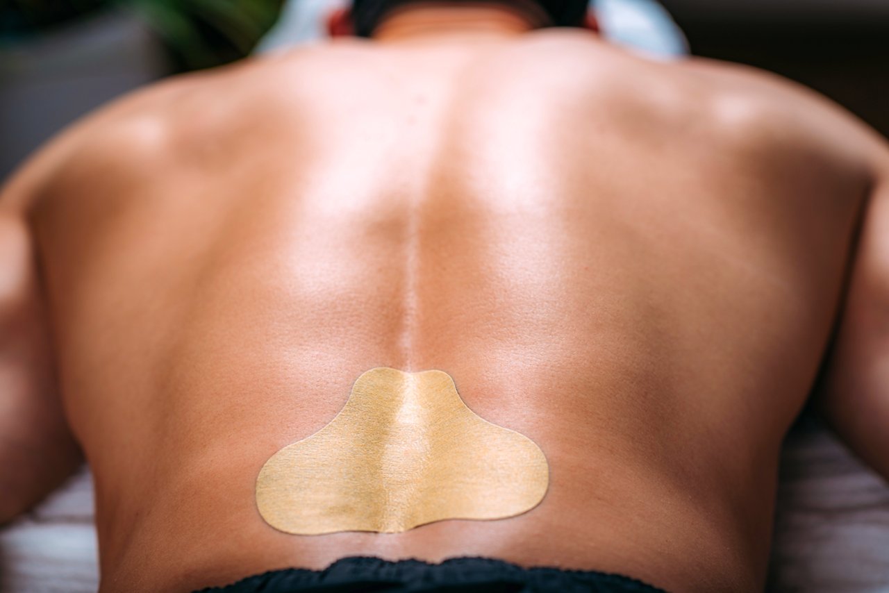 Upper back of a male patient with a wearable device on his lower back.