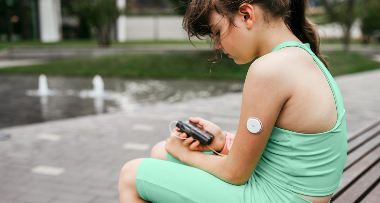 Young girl sitting on a bench while checking her wearable device on her upper arm.