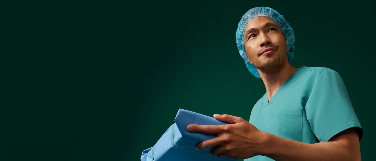 Portrait of a sterilization processing technician stocking inventory on a dark green background.