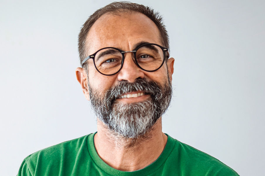 An image of a man in a green shirt with glasses smiling at the camera